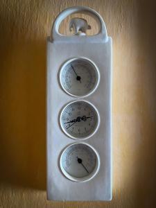 a white clock with three gauges on a wall at La Casa d’Amelia in Ceparana