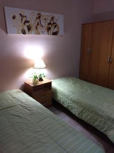 1 dormitorio con 2 camas y mesita de noche con lámpara en departamento 4 personas en San Rafael