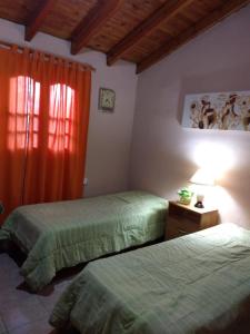 1 dormitorio con 2 camas y cortina roja en departamento 4 personas en San Rafael