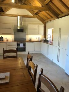 a kitchen with white cabinets and a table and chairs at Old Tynribbie House - Comfortable Detached House in Appin