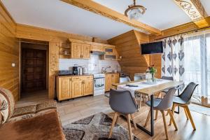 a kitchen with wooden cabinets and a table and chairs at Apartamenty u Bacy in Jurgów