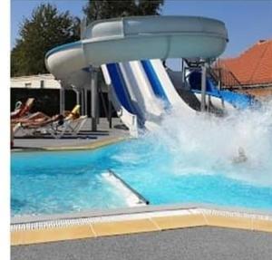 un tobogán de agua en una piscina con gente en ella en le mobile home Le Victory situé au Camping Le Rio en Noyelles-sur-Mer