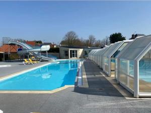 een zwembad met een glijbaan naast een gebouw bij le mobile home Le Victory situé au Camping Le Rio in Noyelles-sur-Mer