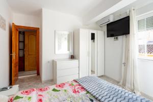 1 dormitorio con 1 cama y TV de pantalla plana en Rooms Breeze & Sun, en Málaga
