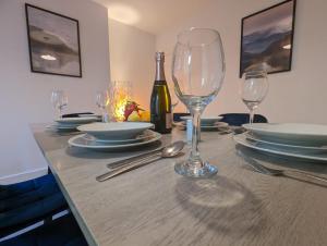 una mesa con copas y platos y una botella de vino en 3 Bed 2 Lounge House up to 40pc off Monthly in Addlestone by Angel and Ken Serviced Accommodation Great Value for Long-term Stay en Addlestone