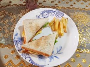 un plato blanco con un sándwich y papas fritas en Purple Guesthouse en Nasugbu