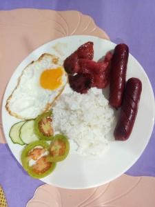 a plate of breakfast food with sausage rice and eggs at Purple Guesthouse in Nasugbu