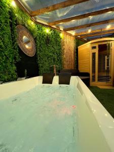a table in a backyard with a green wall at SPA de charme 6 pers avec Jacuzzi & Sauna privatifs au coeur de ville - Esprit Coco in Mulhouse