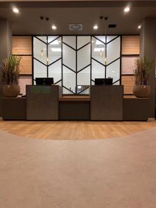 a lobby with a reception desk with potted plants at VIA PLAZA Hotel Meppen in Meppen