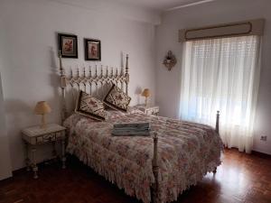 a bedroom with a bed and a window with curtains at familiahorta in Coimbra