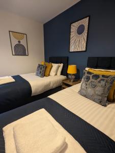 two beds in a room with blue walls at 3 Bed 2 Lounge House up to 40pc off Monthly in Addlestone by Angel and Ken Serviced Accommodation Great Value for Long-term Stay in Addlestone