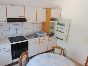 a kitchen with a table and a stove and a sink at Apartman Tomić - Copacabana Beach Okrug Gornji in Okrug Gornji