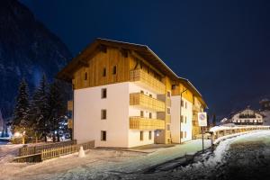 a building with a wooden roof in the snow at Bilocale Fiore in Campitello di Fassa