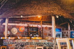 a bar with a straw roof and a brick wall at Kilimanjaro Scenic Lodge in Moshi