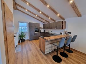 - une cuisine avec un comptoir en bois, une table et des chaises dans l'établissement Alpen Aparts Alteck, à Rauris