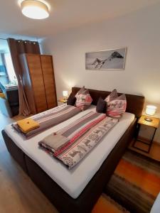 Una cama con mantas y almohadas encima. en Bergperle Apartments & Mountain Sport, en Fliess
