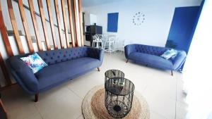 a living room with two blue couches and a table at 3bed villa with private pool and rooftop with a sea view in flic-en-flac, Mauritius in Flic-en-Flac