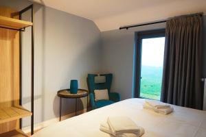 ein Schlafzimmer mit einem Bett, einem Stuhl und einem Fenster in der Unterkunft Gîte XXV House - 4 personnes in Héron
