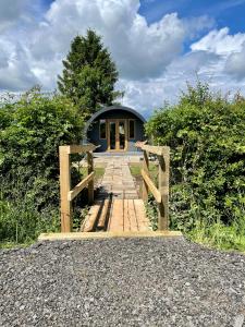 a small blue building with a wooden walkway leading to it at Park Hill Pod in Stratford-upon-Avon