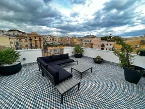 un patio con divano e tavolo sul balcone. di Gioiamia - Luxury Rooms in Cattedrale a Palermo