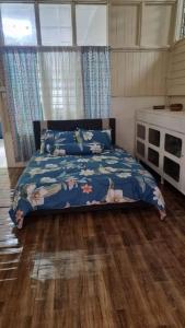 Schlafzimmer mit einem Bett mit blauer Decke in der Unterkunft Teratak An Nur: A village on top of the hill in Kuala Pilah