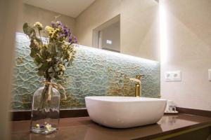 ein Badezimmer mit einem Waschbecken und einer Vase mit Blumen darin in der Unterkunft Apartamentos Las Alas in Cartes