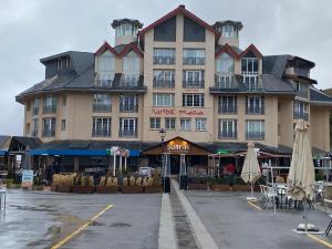 un gran edificio en un aparcamiento con mesas y sombrillas en Duplex 3 dormitorios en plaza de Andalucía, en Sierra Nevada