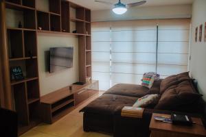 uma sala de estar com um sofá e uma televisão de ecrã plano em Apartamento Rio das Ostras, Extensão do Bosque em Rio das Ostras