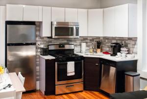 uma cozinha com electrodomésticos de aço inoxidável e armários brancos em Gorgeous 1BR Wooster Sq. apt. - wshr/dryr, parking em New Haven