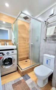 a bathroom with a washing machine and a toilet at Уютные апартаменты in Almaty