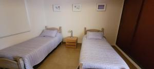two twin beds in a room with a table at Dúplex amplio y luminoso in San Fernando del Valle de Catamarca