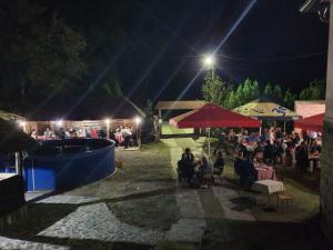 uma multidão de pessoas sentadas às mesas à noite em Vila Krasava em Krupanj