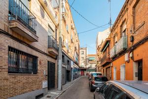 a narrow street with cars parked on the side of buildings at Global Home-Pico Cebollera in Madrid