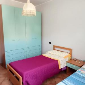 a bedroom with a purple bed and a blue cabinet at Country-House vista montagna in Foce
