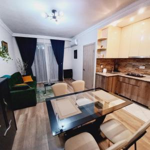 a living room with a glass table and a kitchen at NG Cozy App in Tbilisi City