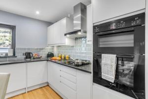 a kitchen with white cabinets and black appliances at Isabel’s wing! A stunning 2 bedroom annex in Norwich