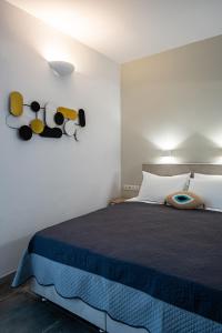 een slaapkamer met een bed met een blauwe deken en hoeden aan de muur bij Dilion Hotel in Parikia