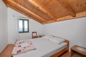 1 dormitorio con cama blanca y techo de madera en House Mirta en Pašman