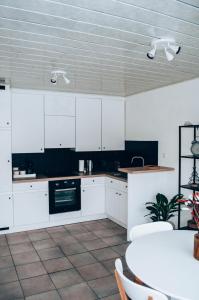 una cocina con armarios blancos y una mesa con sillas. en Vakantieappartement DE SPUIKOM, en Ostende