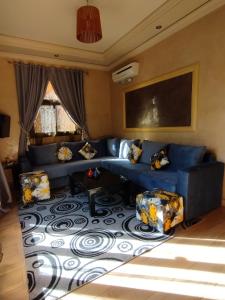 uma sala de estar com um sofá azul e cadeiras em ApartHotel Nzaha em Tahannout