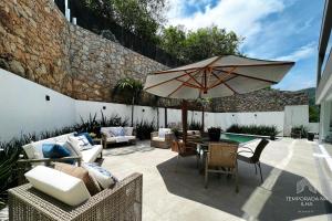 フロリアノポリスにあるCasa moderna com piscina em Floripa - caminho das praiasのパティオ(パラソルと椅子付きのテーブル付)