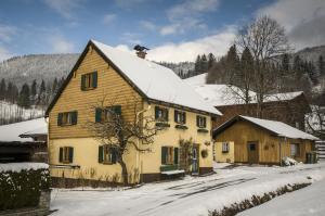 a large yellow house with snow on it at Romantikhäuschen zum Dachsteinblick in Abtenau