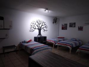 a room with three beds and a tree on the wall at FlipFlops and TreeTops in Jeffreys Bay