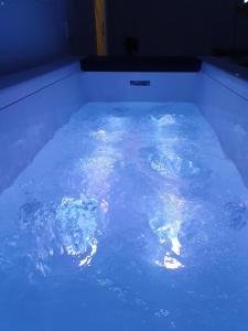 a bathtub filled with blue water with rocks in it at SPA Détente jacuzzi cinéma farniente in Dugny