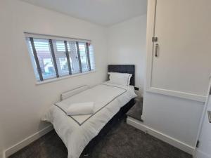 biała sypialnia z łóżkiem i oknem w obiekcie Elm Park Cheerful 4-Bedroom Holiday Home w mieście Hornchurch