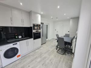 a kitchen with a table and a washing machine in it at Elm Park Cheerful 4-Bedroom Holiday Home in Hornchurch