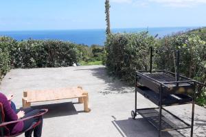 a person sitting in a chair with a barbecue grill at A Barraka: your cozy house in Flores! in Lajes das Flores