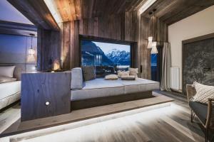 a bedroom with a couch and a large window at Margarethenstein Boutique Hotel in Kaprun