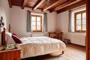 a bedroom with a large bed and two windows at Rifugio Malga Ra Stua in Cortina dʼAmpezzo