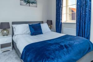 諾丁漢的住宿－6 bedroom Astan House in Beeston Nottingham，一间卧室配有一张带蓝色窗帘的床和一扇窗户
